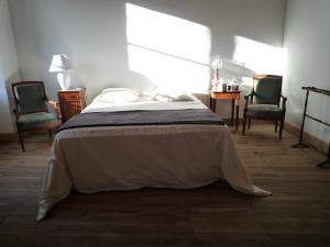 Celles-sur-BelleLe Logis de Miserè的一间卧室配有一张带两把椅子和一张桌子的床。