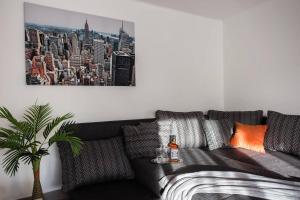 佩奇Csigaház Apartman的客厅配有一张黑色沙发,并可欣赏城市的画面