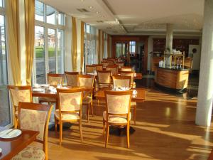 贝塞尔Vier Jahreszeiten Bensersiel的餐厅设有木桌、椅子和窗户。