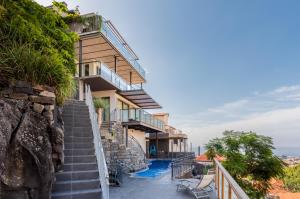 丰沙尔Number 15 Ocean & City View Villas的悬崖上的房子,设有楼梯和游泳池