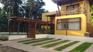 伊塔卡雷Conchas do Mar Residence的黄色的房屋,设有木制凉棚