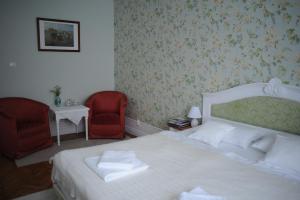 奥拉迪亚Sophie Apartment的一间卧室配有白色的床和两张红色椅子