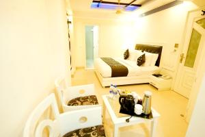 新德里THE SINGH EMPIRE, New Delhi的一间小卧室,配有一张床和一张桌子及四柱床