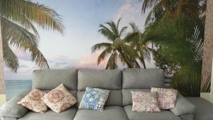 阿里纳加CanariasBrisaMar - Apartamento的棕榈树壁画前的沙发,配有枕头