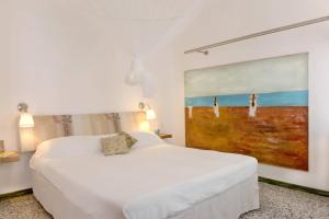 泰塞拉CASA DI ROBY - VENICE AIRPORT的卧室配有一张白色床,墙上挂有绘画作品