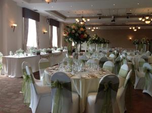 斯旺西塔楼温泉酒店的宴会厅配有白色的桌椅和鲜花
