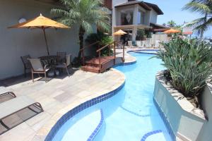 瓜鲁雅Hotel Ilhas do Caribe - Na melhor região da Praia da Enseada的一个带桌子和遮阳伞的游泳池