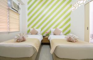 宿务艾丽西亚塔沃旅舍的绿白带的客房内的两张床