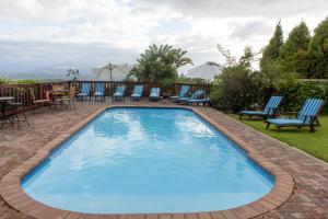 普利登堡湾Whalesong Hotel & Spa的一个带桌椅的大型蓝色游泳池