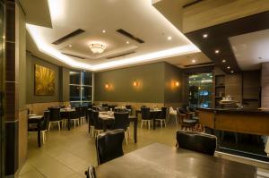 拉布安Mariner Hotel Labuan的一间带桌椅的餐厅和一间酒吧