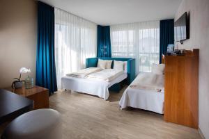 埃尔丁Victory Gästehaus Therme Erding的酒店客房,设有两张床和蓝色窗帘
