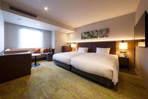 金泽Hotel Forza Kanazawa的酒店客房设有一张大床和一张沙发。