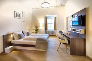 克罗纳赫JUFA Hotel Kronach – Festung Rosenberg的一间卧室配有一张床、一张书桌和一台电视