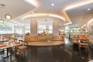 雅加达雅加达太贝特哈里斯酒店的餐厅设有木桌、椅子和柜台