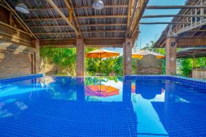 会安Calm House Hotel Hoi An 1的一个带遮阳伞和遮阳伞的室外游泳池