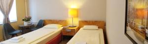 柏林M68酒店的客房设有两张床、一张桌子和一盏灯。