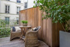 巴黎喜登酒店的庭院设有两把椅子、一张桌子和围栏