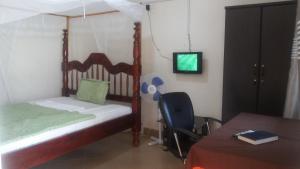 AdjumaniDubai Resort Hotel的一间卧室配有一张床、一张桌子和一台电视。