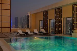 多哈Dusit Doha Hotel的酒店带椅子的游泳池,享有城市美景