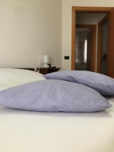 里米尼LA CASA DELLE CONCHIGLIE ombrellone, parcheggio e uso di biciclette gratis的床上铺有紫色枕头的床