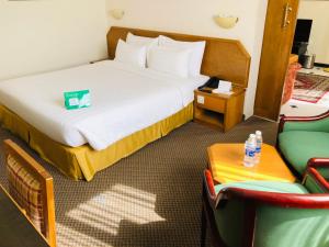 马斯喀特地那假日酒店的酒店客房带一张床、一张桌子和椅子