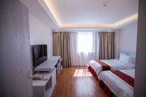 加拉班Hotel Americano的酒店客房设有两张床、一张桌子和一台电视。