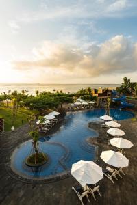 努沙杜瓦美乐滋海水浴海滨度假村巴厘岛全包酒店的一个带遮阳伞和海洋的游泳池的度假酒店