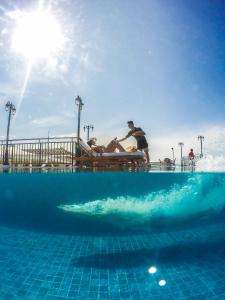 长滩岛Feliz Hotel Boracay的坐在游泳池旁长凳上的男人