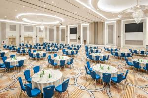 吉达雷迪森广场吉达酒店的一个带桌子和蓝色椅子的大型宴会厅