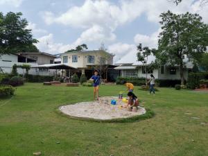 大城Baan Suan Krung Kao的一群孩子在院子里的沙箱里玩耍