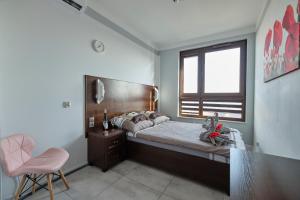 弗罗茨瓦夫Lux Apartment Center的一间卧室设有一张床、一个窗口和一张粉红色的椅子
