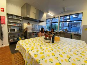 珀斯Downtown Backpackers Hostel Perth - note - Valid Passport required for check in的一群人在厨房里,一边桌子一边