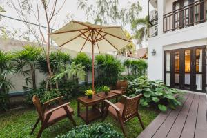 清迈El Barrio Lanna- SHA Extra Plus的庭院配有桌椅和遮阳伞。
