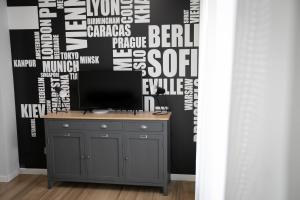 贝加莫Donizetti Residence的客房设有一张桌子、一台电视和一堵文字覆盖的墙