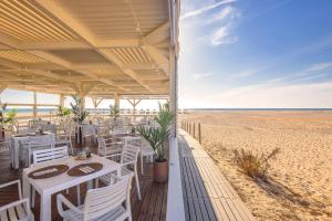 萨阿拉德洛斯阿图内斯Meliá Zahara Resort & Villas的海滩上的餐厅,配有桌椅