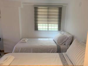 门多萨Alquiler temporario Mendoza的白色的卧室设有床和窗户