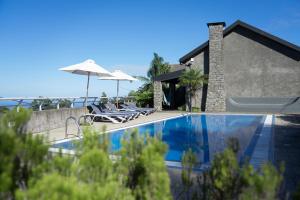 圣若热岛卡萨达斯普罗提斯酒店的房屋旁的游泳池配有椅子和遮阳伞