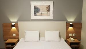 圣洛伦索布拉格中央酒店的一张带两个枕头的床和一张墙上的照片