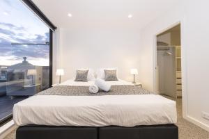 墨尔本Q Squared Serviced Apartments的一间卧室设有一张大床和一个大窗户