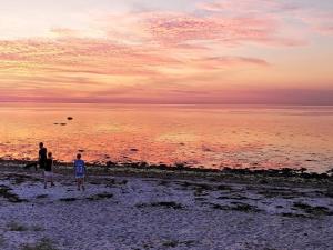 格莱斯堡8 person holiday home in Glesborg的日落时分两人站在海滩上