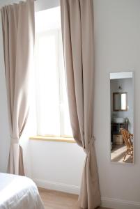 蒙泰罗通多L'Alighieri的一间卧室设有窗户,配有窗帘和镜子