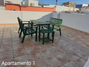 大加那利岛拉斯帕尔马斯Apartamento Kings Vegueta的屋顶上设有两张绿色椅子和一张桌子