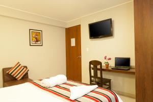 瓦努科Mauri的酒店客房配有一张床、一张书桌和一台笔记本电脑