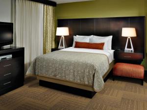 约翰逊城Staybridge Suites - Johnson City, an IHG Hotel的一间卧室配有一张床、两盏灯和一台电视。