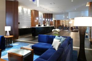 熊本ANA Crowne Plaza Kumamoto New Sky, an IHG Hotel的客厅设有蓝色的沙发和酒吧。