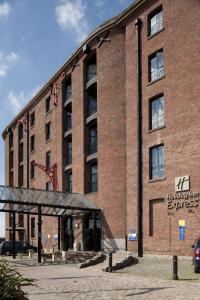 利物浦快捷假日利物浦阿尔伯特码头酒店的一座大型红砖建筑,上面有标志
