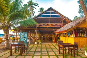 亭可马里COCONUT BEACH LODGE的海滩上的餐厅,配有桌椅