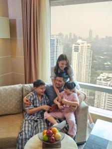 马尼拉Shangri-La The Fort, Manila的坐在客厅沙发上的女人和三个孩子