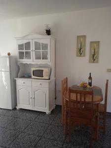 波多·纳奥斯Apartamento MINI 1的厨房配有白色橱柜、桌子和微波炉