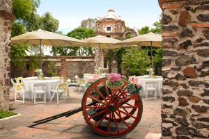Villa del PueblitoHotel Ex Hacienda La Pitaya Querétaro的一个带桌子的庭院上带遮阳伞的木 ⁇ 轮